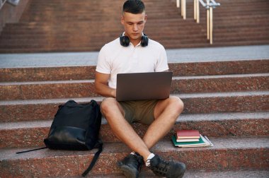 Günlük kıyafetlerle. Genç erkek öğrenci dışarıda..