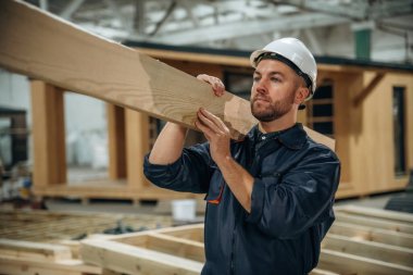 Kalas, adam onu tutuyor. Erkek müteahhit ahşap ev inşaatında..