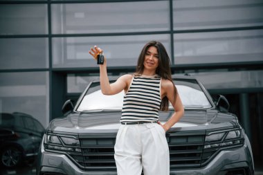 Yeni arabanın anahtarlarını. Mutlu sahip. Çekici genç bayan dışarıda, yepyeni arabasının yanında..