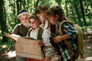 Kağıt harita ellerinde. Çocuklar yazın gündüz vakti ormanda..