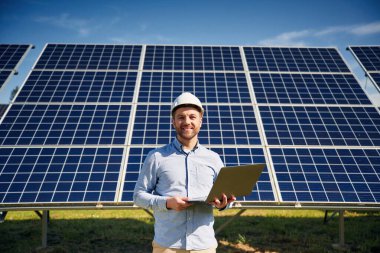 Güneşli bir gün. Dışarıda fotovoltaik güneş panelleri olan bir mühendis..