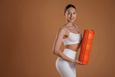 Turuncu renkli fitness rulosu. Güzel kadın stüdyoda..