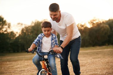 Ata binmeyi öğretiyorum. Baba ve oğul dışarıda bisikletle geziyorlar..