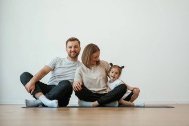 Neşeli insanlar. Anne, baba ve kızı evde yoga yapıyor..