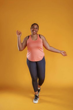 Spor kıyafetleri içinde. Afrikalı Amerikalı kadın sarı arka planda stüdyoda..