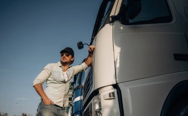 Ön manzara, kabine yaslanma. Kamyon şoförü açık havada nakliye aracının yanında..