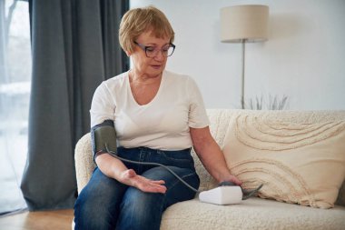 Basınç ölçümü. Yaşlı yaşlı kadın evde, oturma odasında..