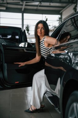 Kapıdan çıkıyorum. Güzel genç bayan araba galerisinde yeni arabasıyla..