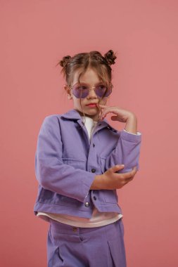 Şık güneş gözlükleriyle. Şirin küçük kız pembe arka plana karşı..