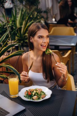 Lezzetli yemekleri tatmak. Güzel, genç bir bayan restoranın dışında, masanın yanında..