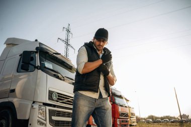 Siyah eldiven giyiyor. Kamyon şoförü açık havada nakliye aracının yanında..