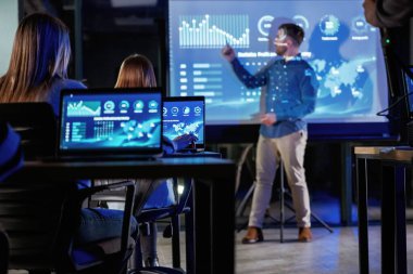 Akıllı koç. Erkek işletme eğitmeni projektöre karşı, insanlara öğretiyor..