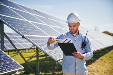Gündüz vakti fotovoltaik güneş panelleri olan profesyonel yetişkin mühendis..