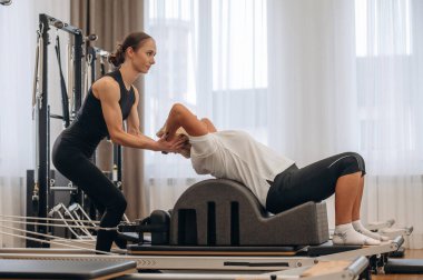 Aktif eğitim. Kadın eğitmen yaşlı kadının egzersiz yapmasına yardım ediyor..