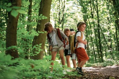 Bir sürü yeşil bitki ve yaprak. Çocuklar yazın gündüz vakti ormanda..