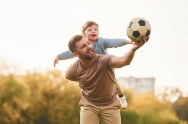 Gerçek futbol, futbol topu. Mutlu baba ve oğul yazın sahada eğleniyorlar..