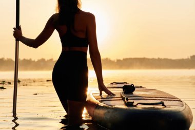 Muhteşem günbatımı, ayakta ve bakıyor. Genç kadın gölde yemek masasında..