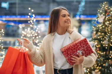 Kırmızı alışveriş torbaları. Yeni yıl hediyeleri. Kadın Noel ağacının yanında..