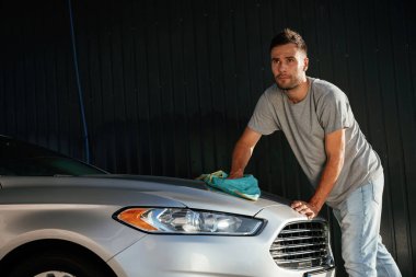 Yandan bak, otomobili parlatmak için bez kullan. Adam dışarıda arabasıyla bekliyor..