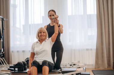 Silah egzersizi. Kadın eğitmen yaşlı kadına yardım ediyor..