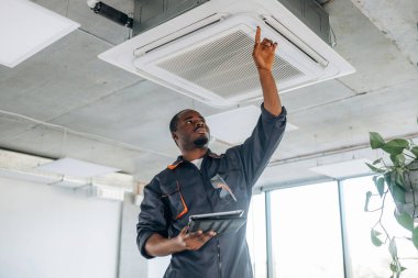 Elleri yukarıda, havalandırmayı tamir ediyorlar. Tamirci modern ofiste kapalı bir yerde..