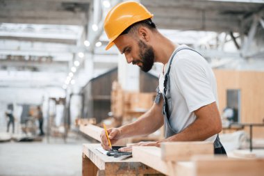 Sarı kalem, bölgeyi işaretle. Ahşap depoda sanayi işçisi..