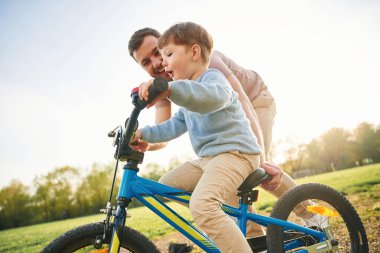 Mavi bisiklete binmek. Mutlu baba ve oğul yazın sahada eğleniyorlar..