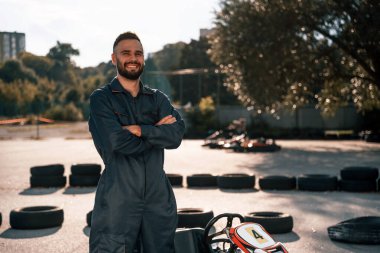 Aracın ve ağaçların karşısında duruyor. Erkekler açık havada, kart yarışı gebeliği..