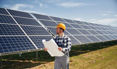 Planlı büyük kağıt, okumak. Gündüz vakti fotovoltaik güneş panelleri olan bir mühendis..