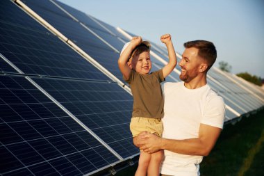 Beyaz başlık. Baba ve küçük oğlu güneş panellerinin yakınındalar..
