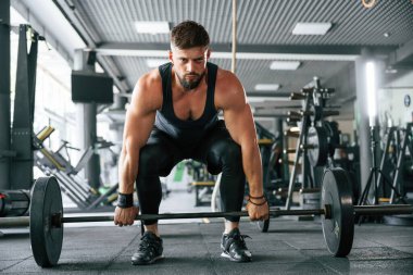 Halter kaldırıyor. Güçlü kaslı adam spor salonunda çalışıyor..