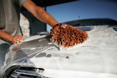 Beyaz temizlik kimyasalı, otomobili yıkamak. Adam dışarıda arabasıyla bekliyor..