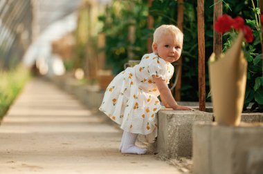 Tatlı bir kız çocuğu kırmızı çiçeklerle serada..