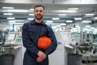 Mola zamanı, ayakta. Fabrika işçisi kasketli bir şekilde içeride..