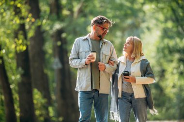 Ellerinde kahve fincanları, etrafta dolanıyorlar. Doğada üst düzey çiftler birlikte..