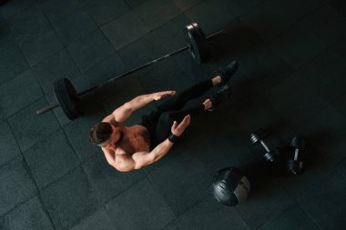 Yukarıdan bak. Güçlü kaslı adam spor salonunda çalışıyor..