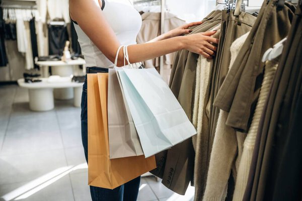 Мешки для покупок в руке. Закрыть глаза на женщину, которая душит одежду в магазине розничной торговли.