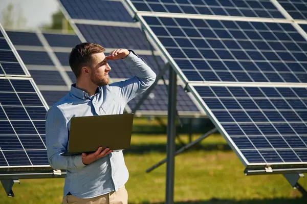 Dizüstü bilgisayarı tutuyorum. Gündüz vakti fotovoltaik güneş panelleri olan bir mühendis..