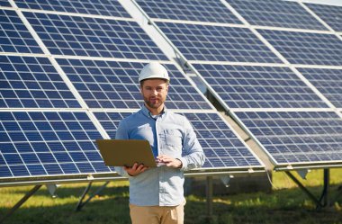 Dizüstü bilgisayarla. Gündüz vakti fotovoltaik güneş panelleri olan bir mühendis..
