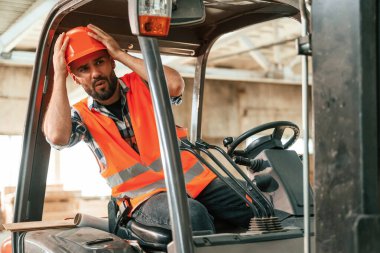 Forkliftte oturuyor. Ahşap depoda sanayi işçisi..