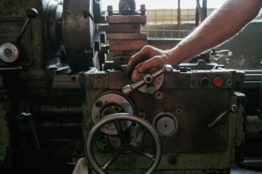 Meşgul adam. Atölyede endüstriyel makineleri çalıştıran işçilerin yakın çekimi.