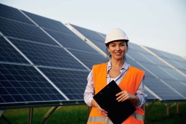Üniformalı kadın işçi mühendisi güneş panellerinin yakınında..