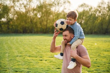 Futbol topuyla. Mutlu baba ve oğul yazın sahada eğleniyorlar..