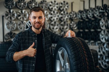 Gülümseme, pozitif yüz ifadesi, el hareketi. Tekerlekleri ve tekerlekleri olan tamirci var..