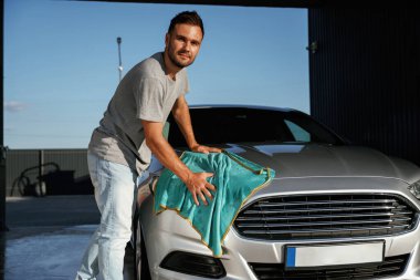 Turkuaz kumaş, aracı cilalama. Adam dışarıda arabasıyla bekliyor..