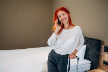 Telefonla konuşuyorlar. Kadın otel odasında, modern iç mekan..