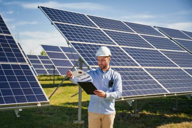 Güneşli bir gün. Dışarıda fotovoltaik güneş panelleri olan bir mühendis..