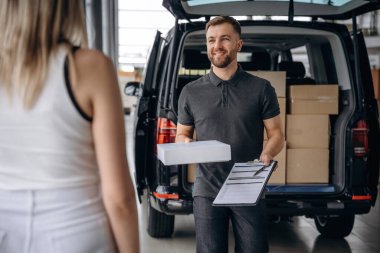 Müşteri siparişini alıyor. Kadın teslimatçıyla, arabayla..