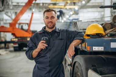 Mola veriyoruz, bir bardak içkiyle. Erkek işçi, modern depo veya imalat şirketinde çalışıyor..