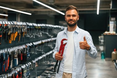 Kırmızı boru anahtarı. Adam hırdavatçıda..